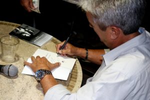 Carlos A. Dueñas firma ejemplares, durante la presentación.